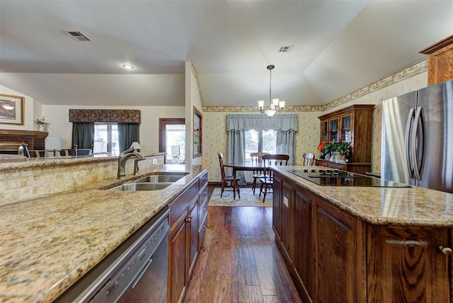 kitchen featuring stainless steel appliances, visible vents, vaulted ceiling, a sink, and wallpapered walls