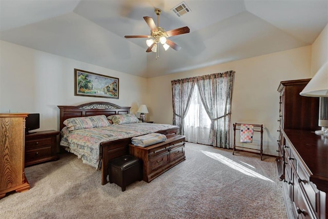 bedroom with lofted ceiling, ceiling fan, light carpet, visible vents, and a tray ceiling