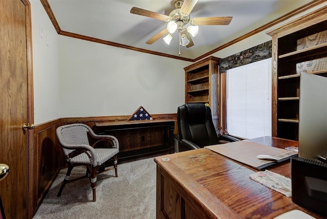 carpeted office space featuring ceiling fan, wooden walls, wainscoting, and crown molding