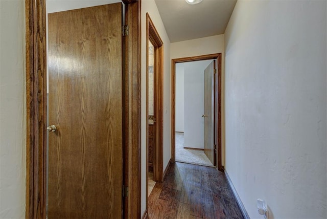 hallway featuring baseboards and dark wood-style flooring