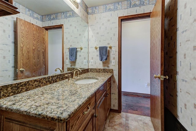 bathroom with wallpapered walls, baseboards, and vanity