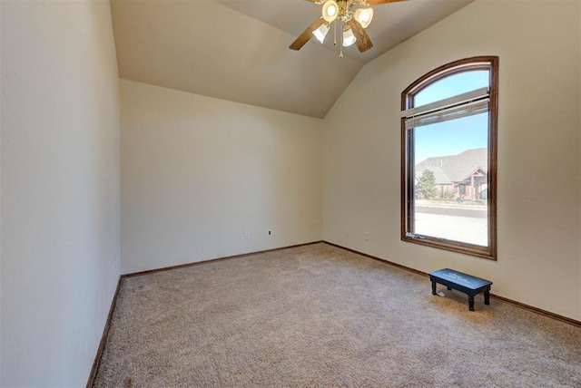 empty room featuring vaulted ceiling, carpet, a ceiling fan, and baseboards