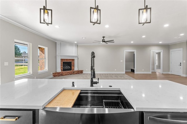 kitchen with light stone counters, hanging light fixtures, a fireplace, and ornamental molding