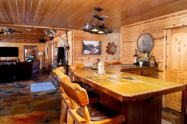 dining area featuring ceiling fan, wooden ceiling, and wooden walls