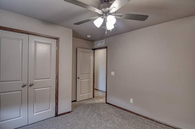 unfurnished bedroom featuring ceiling fan, light colored carpet, and a closet