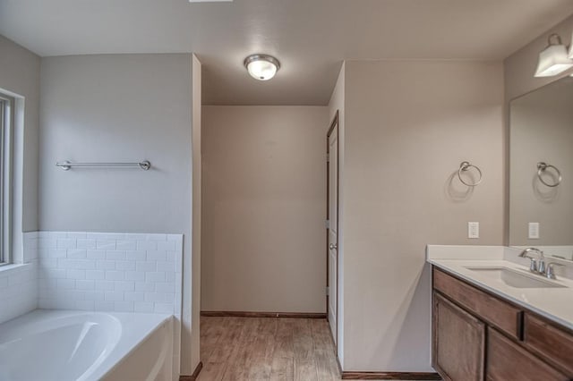 bathroom featuring vanity, wood-type flooring, and a tub