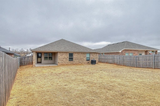 rear view of house with cooling unit, a lawn, and a patio area