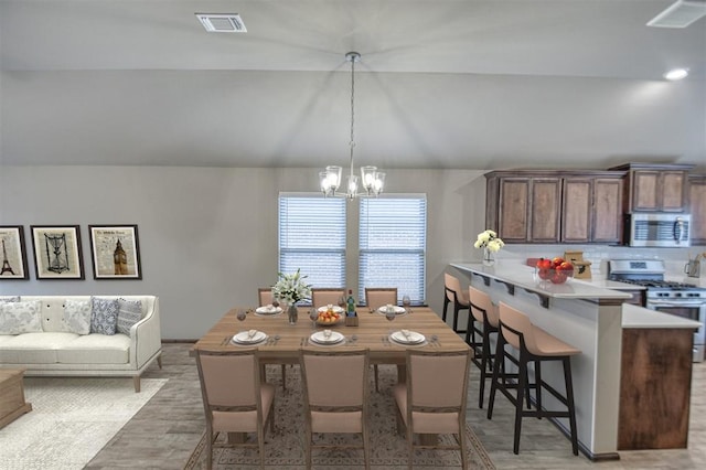 dining space with wood-type flooring, lofted ceiling, and an inviting chandelier