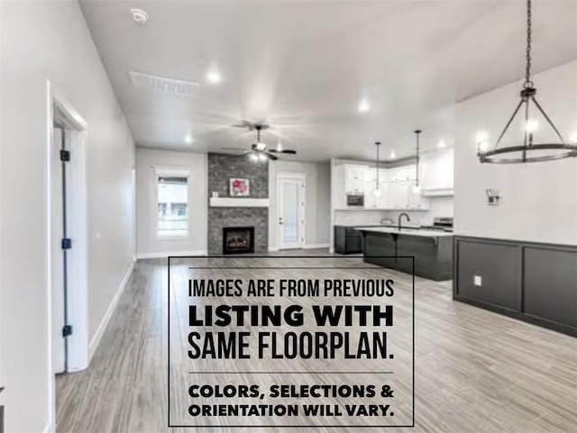 interior space with sink, ceiling fan with notable chandelier, light hardwood / wood-style floors, and a large fireplace