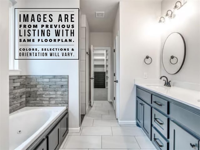 bathroom with a tub to relax in, vanity, and tile patterned flooring