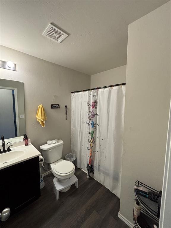 bathroom featuring walk in shower, vanity, toilet, and hardwood / wood-style floors