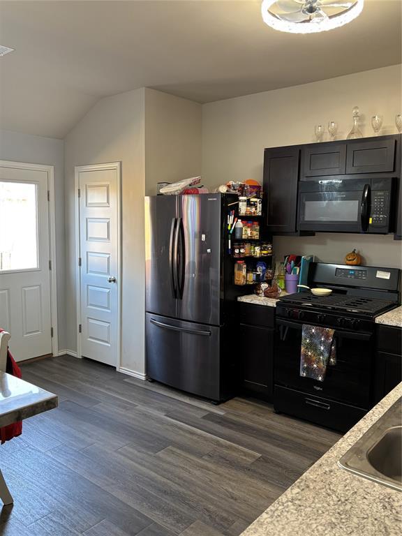 kitchen featuring vaulted ceiling, sink, dark hardwood / wood-style flooring, and black appliances