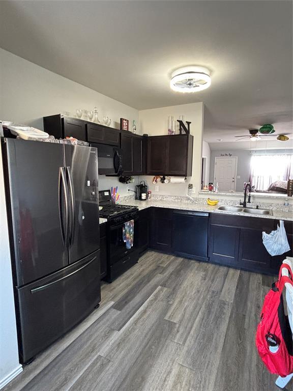 kitchen with sink, hardwood / wood-style flooring, ceiling fan, black appliances, and light stone countertops