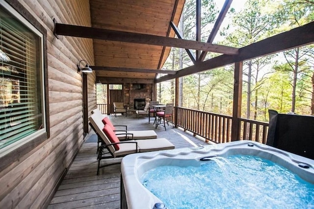 wooden terrace featuring an outdoor hot tub and an outdoor stone fireplace