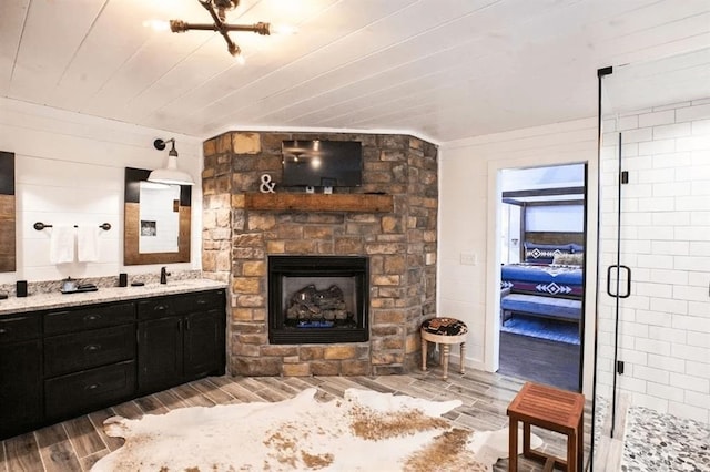 bathroom with vanity, a stone fireplace, a shower with door, and wooden ceiling