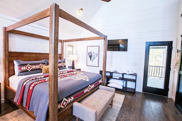 bedroom with high vaulted ceiling, wooden walls, and dark hardwood / wood-style flooring