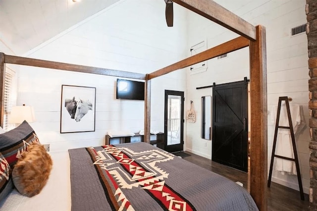 bedroom with dark wood-type flooring, lofted ceiling with beams, a barn door, and ceiling fan