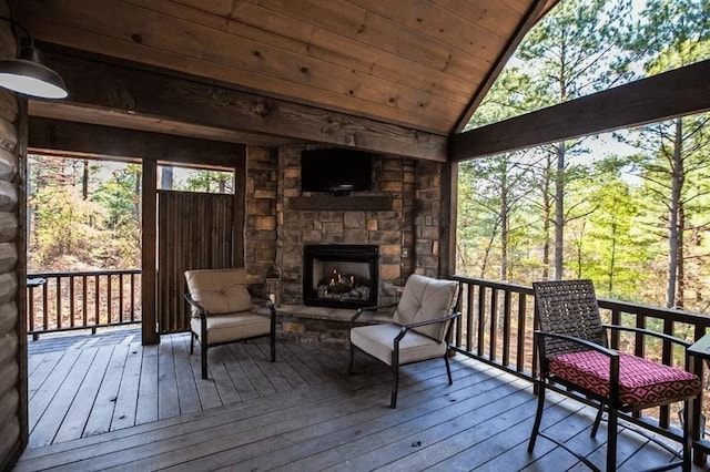 sunroom / solarium with lofted ceiling, wood ceiling, and a stone fireplace