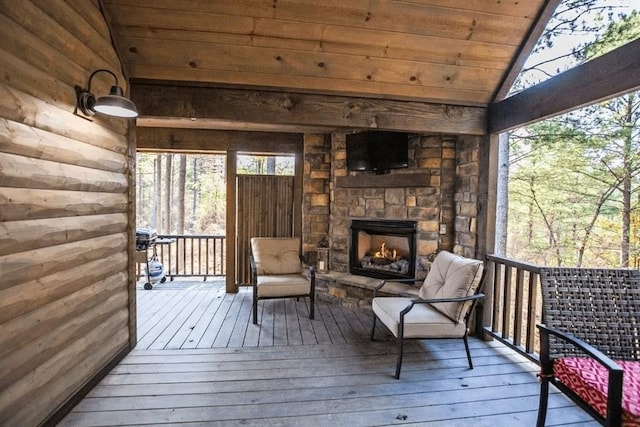 wooden deck featuring an outdoor stone fireplace