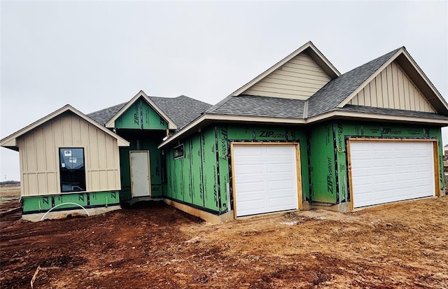 unfinished property with board and batten siding and a shingled roof