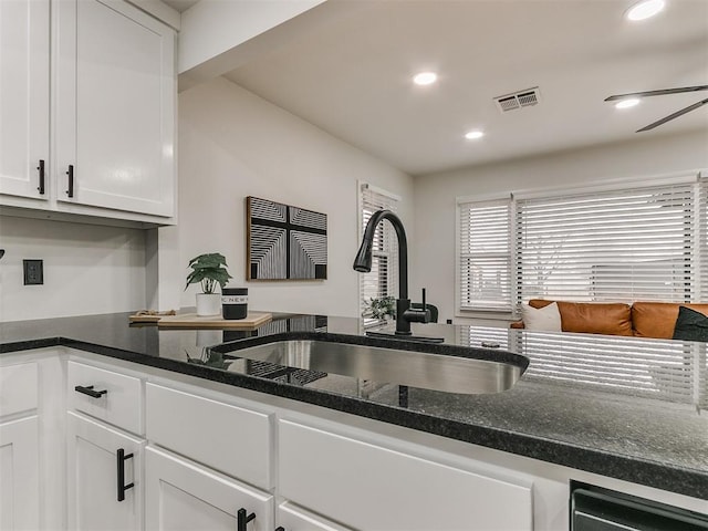 kitchen featuring white cabinetry, ceiling fan, dark stone counters, and sink