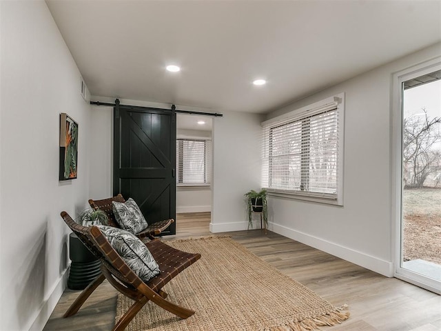 sitting room with a barn door and light hardwood / wood-style flooring