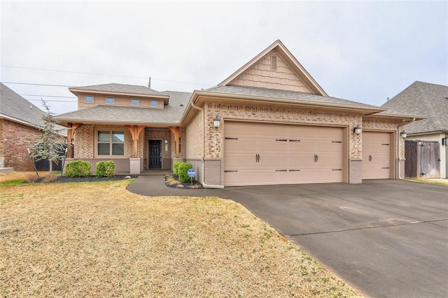 view of front of home featuring a garage, concrete driveway, roof with shingles, a front lawn, and brick siding