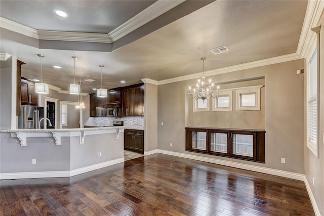 kitchen featuring high end fridge, visible vents, hanging light fixtures, an inviting chandelier, and a kitchen breakfast bar