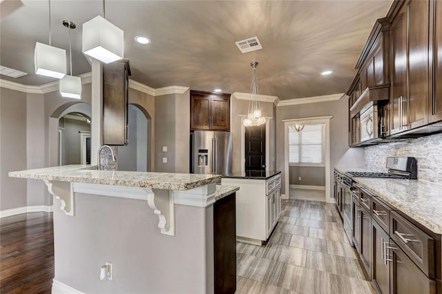 kitchen with stainless steel appliances, tasteful backsplash, visible vents, hanging light fixtures, and a kitchen bar