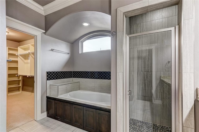 bathroom with a garden tub, a shower stall, ornamental molding, and a walk in closet