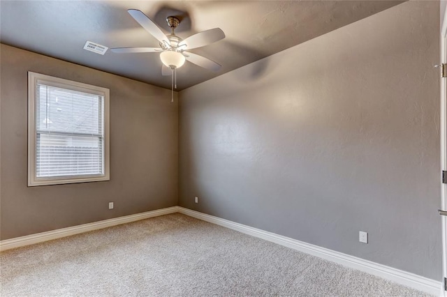 carpeted spare room with a ceiling fan, visible vents, and baseboards