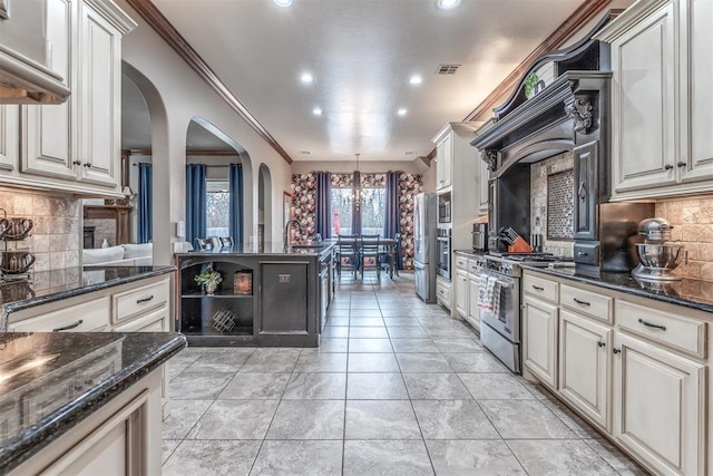 kitchen featuring crown molding, hanging light fixtures, stainless steel appliances, light tile patterned flooring, and dark stone counters