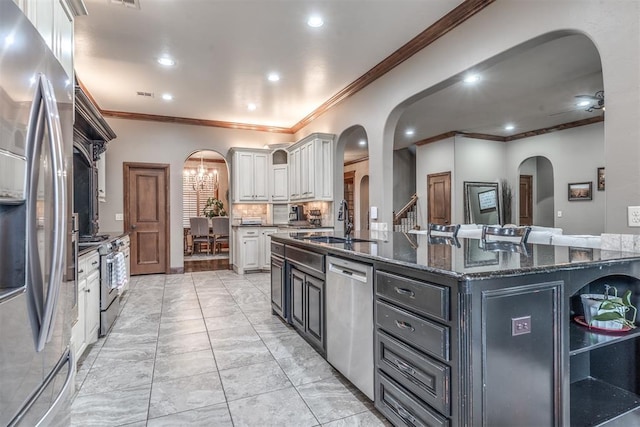 kitchen with a large island, dark stone countertops, backsplash, stainless steel appliances, and white cabinets