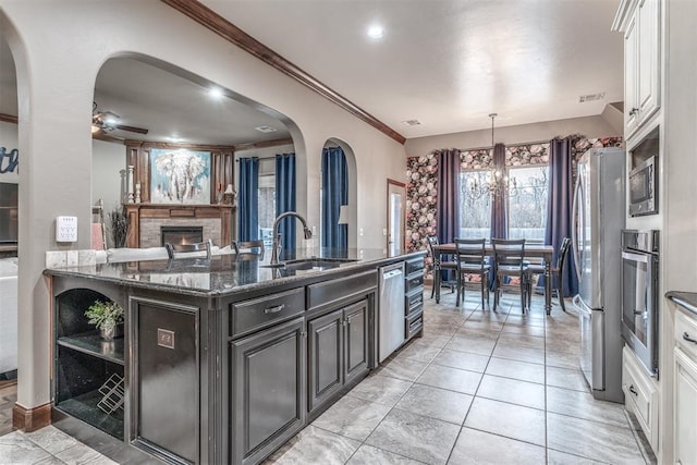 kitchen with stainless steel appliances, white cabinetry, sink, and dark stone countertops