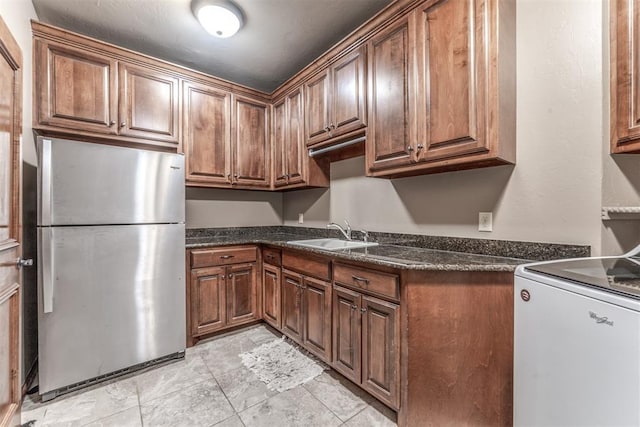 kitchen with sink, range, and stainless steel refrigerator