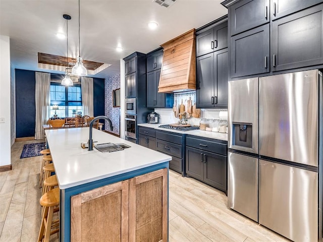 kitchen with sink, a kitchen breakfast bar, stainless steel appliances, custom range hood, and a center island with sink