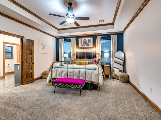 carpeted bedroom with crown molding, ceiling fan, and a tray ceiling