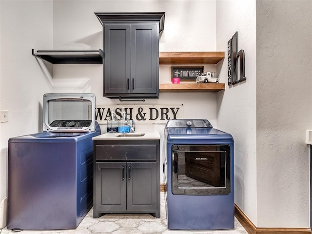 clothes washing area featuring independent washer and dryer, cabinets, and sink