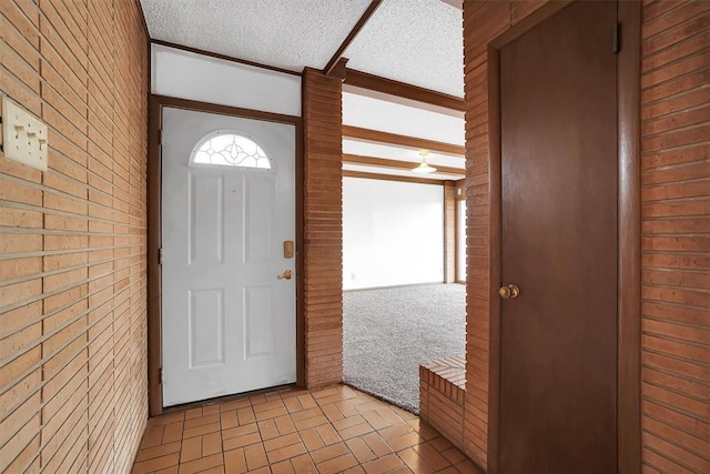 foyer entrance with a textured ceiling and brick wall