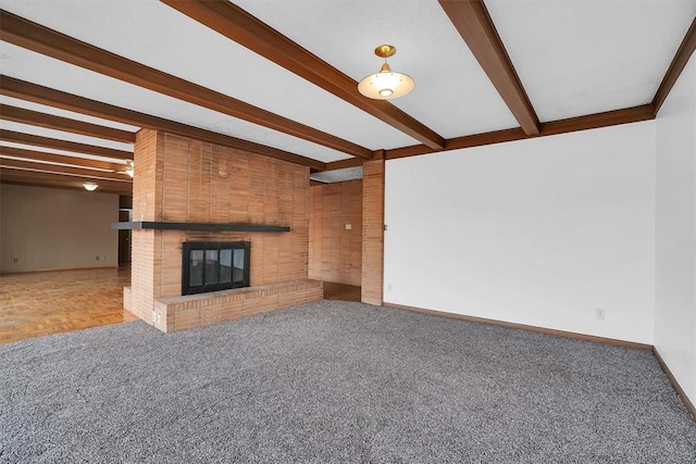 unfurnished living room featuring a brick fireplace, beamed ceiling, and carpet