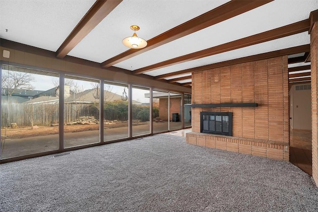 unfurnished living room featuring beam ceiling, a fireplace, and carpet flooring