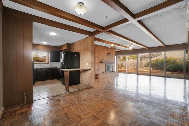 kitchen featuring a textured ceiling, black refrigerator, wooden walls, kitchen peninsula, and light parquet flooring