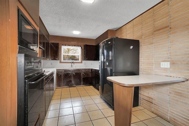 kitchen with sink, black appliances, a textured ceiling, light tile patterned flooring, and kitchen peninsula