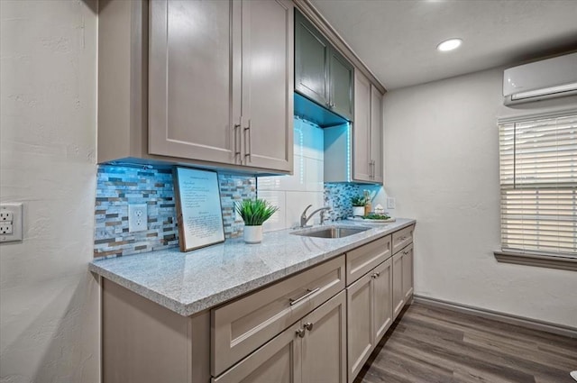 kitchen with light stone countertops, sink, a wall mounted air conditioner, and backsplash