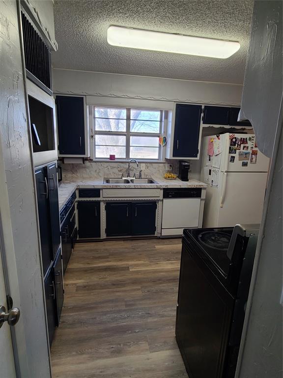 kitchen featuring white appliances, dark hardwood / wood-style floors, sink, and a textured ceiling