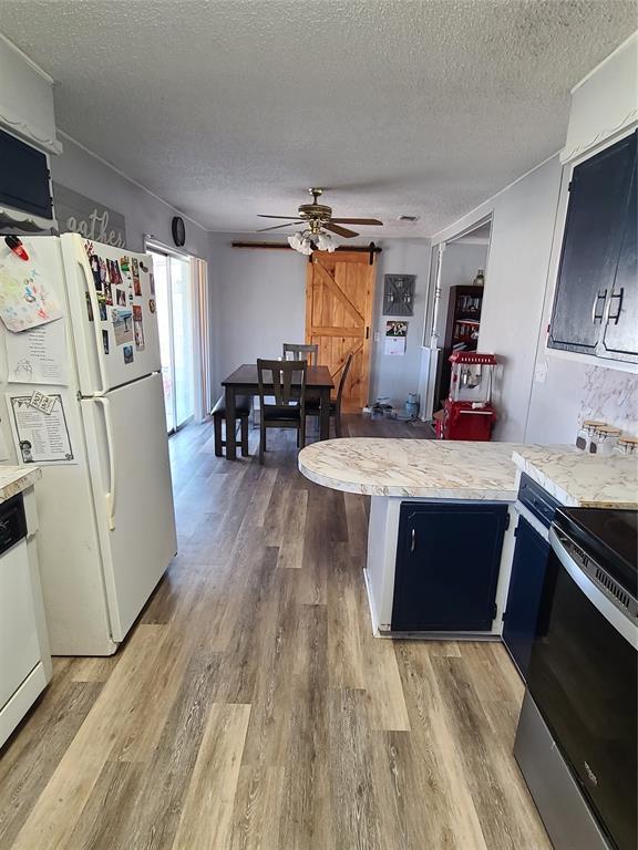 kitchen with white appliances, ceiling fan, hardwood / wood-style floors, a textured ceiling, and kitchen peninsula