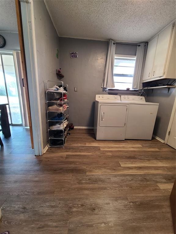 laundry area with cabinets, a textured ceiling, washing machine and clothes dryer, and dark hardwood / wood-style flooring