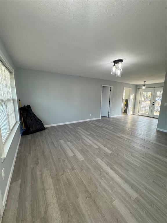 unfurnished room featuring a textured ceiling, light hardwood / wood-style floors, and french doors