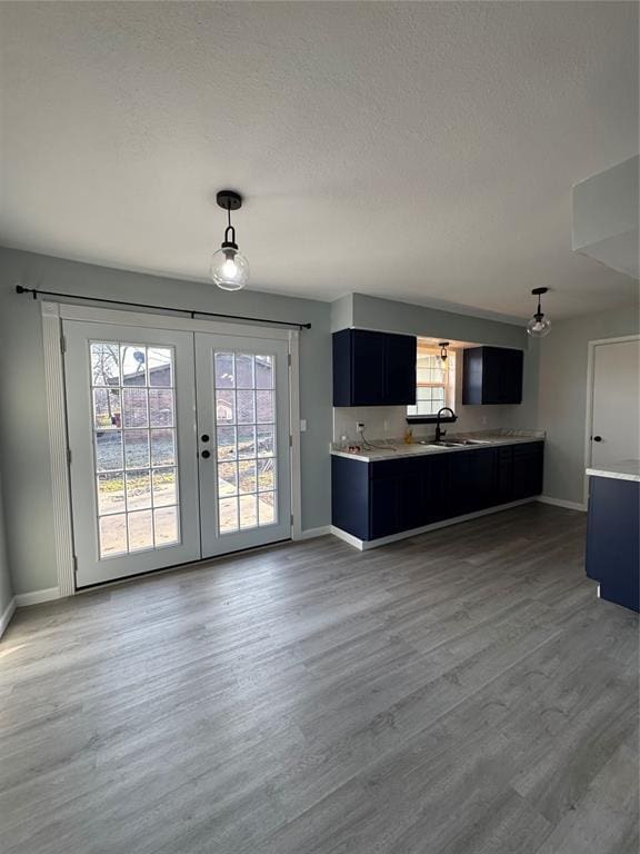 kitchen with pendant lighting, sink, wood-type flooring, a textured ceiling, and french doors