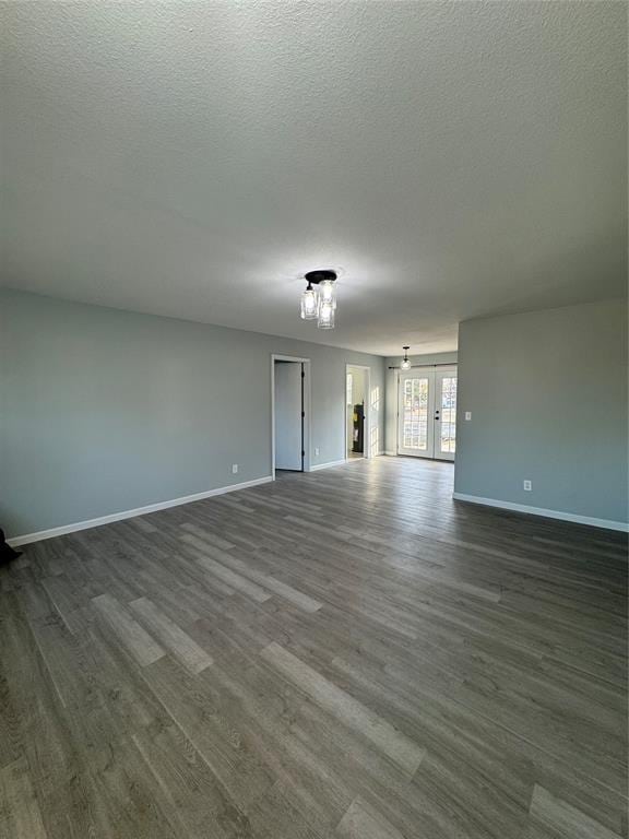 unfurnished room with dark hardwood / wood-style floors, a textured ceiling, and french doors